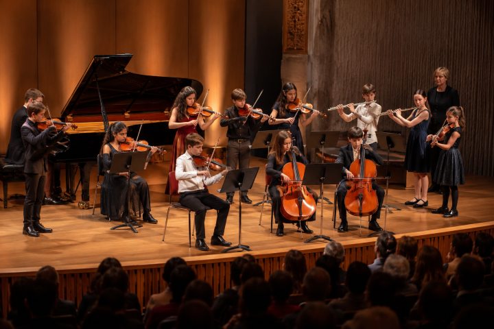 Niños y adolescentes interpretando música en directo durante un concierto de alumnos en Madrid.